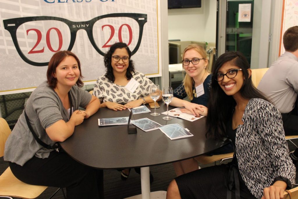 Students at table smiling at networking event