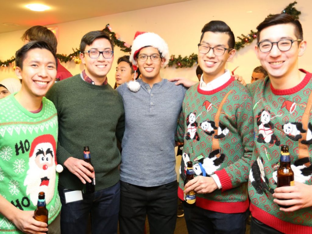 students pose at Optometry Holiday party with holiday sweaters