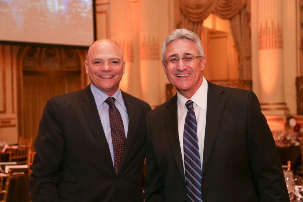 2 men in suits posing for photo