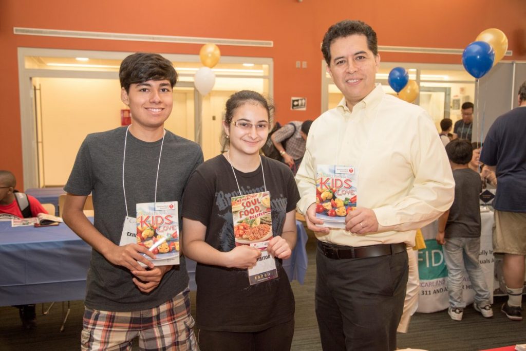 Young girl and boy and adult man holding up brochures