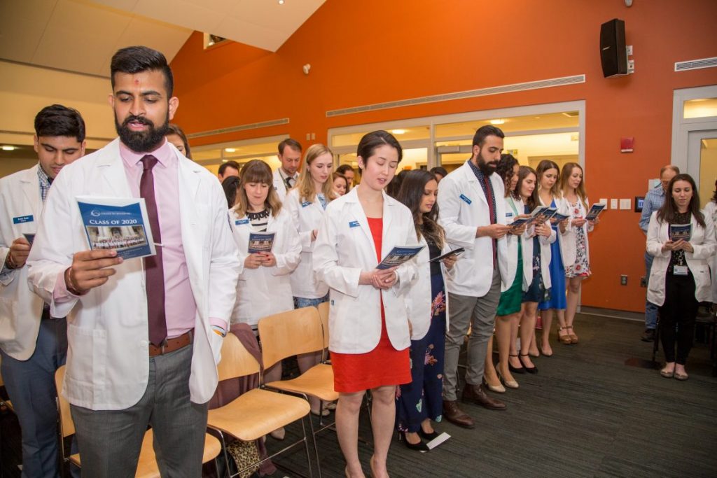 Students in white coats standing